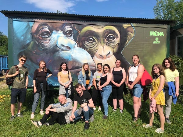 SERC students pictured in front of large mural depicting primates.